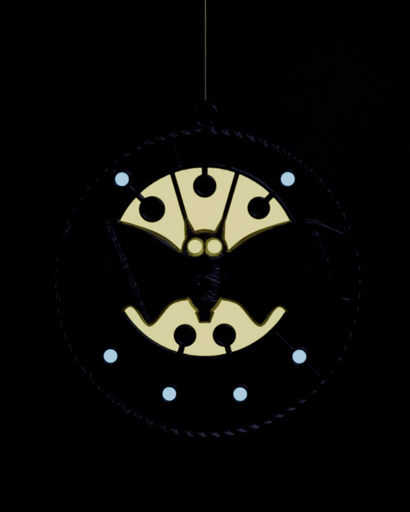 Digital preview with the lights out: the moon glows pale gold around the bat and small stars glow blue