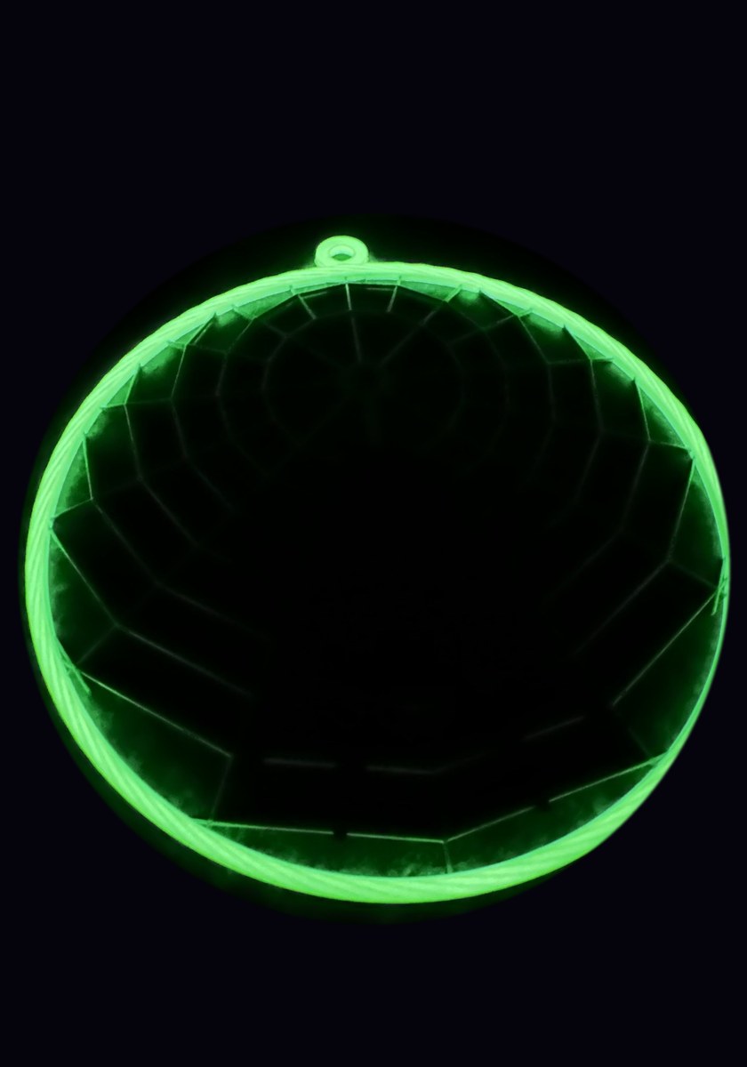 The same web with the lights out: the ring glows bright green